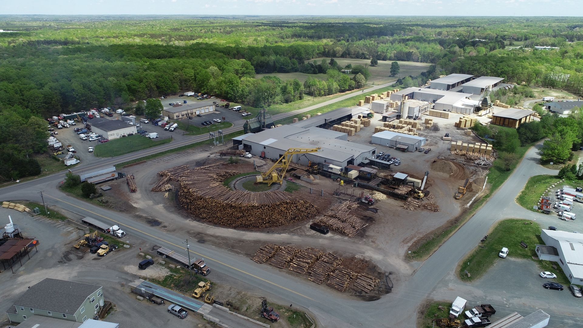 An aerial view of a large pile of logs surrounded by buildings and trees.