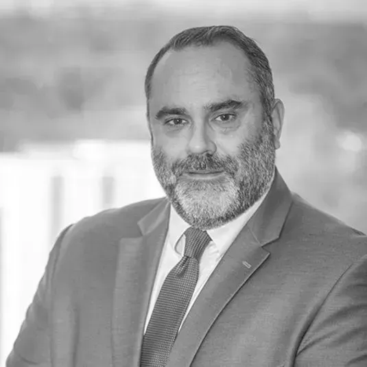A man with a beard is wearing a suit and tie in a black and white photo.