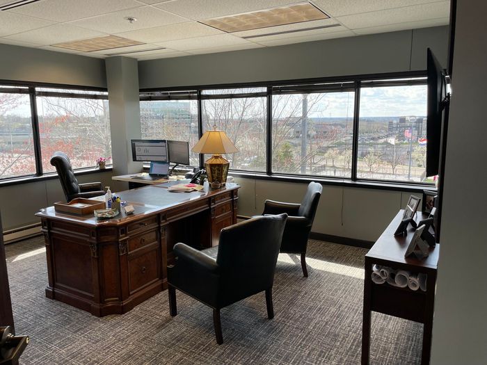 A large office with a desk , chairs , and a television.