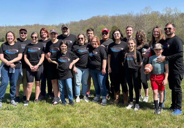 Team photo and families at an outdoor event.