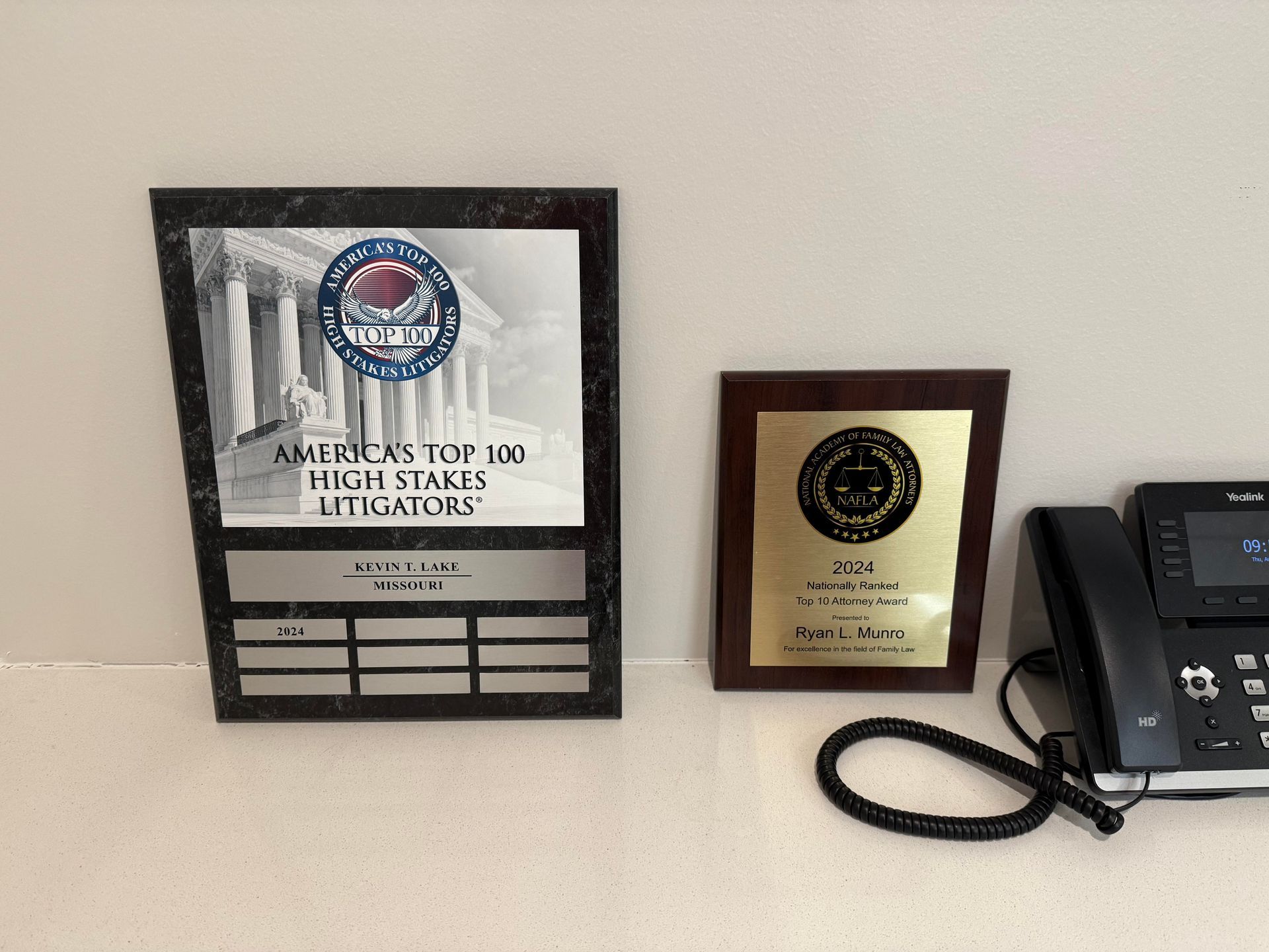 Two plaques with logos and text, and a black telephone on a white surface.