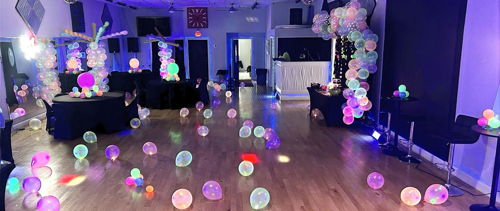 A large room is decorated with glow in the dark balloons and lights.