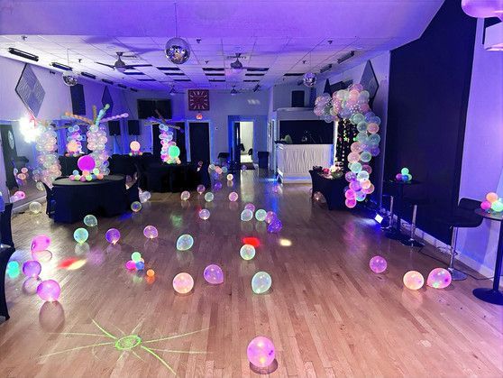 A room is decorated with glow in the dark balloons and lights.