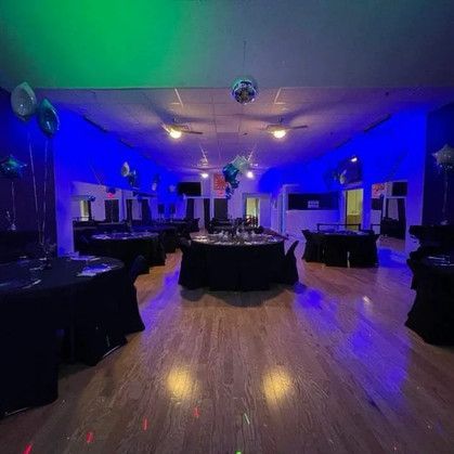 A large room with tables and chairs and balloons on the ceiling.