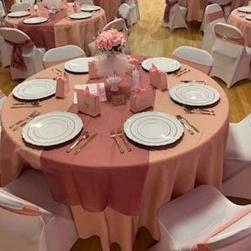 A round table with plates , silverware , and flowers on it is set up for a party.