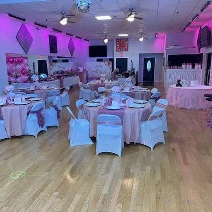 A large room with tables and chairs set up for a party.