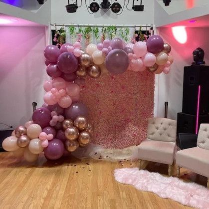 A room filled with balloons and a flower wall.