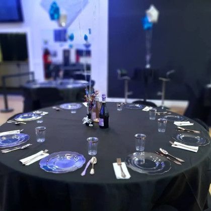 A round table with plates , utensils , and glasses on it.