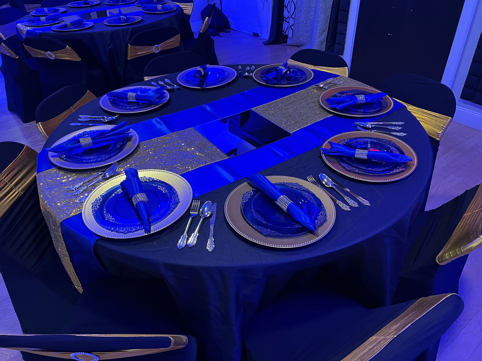 A round table with blue and gold plates and napkins on it.