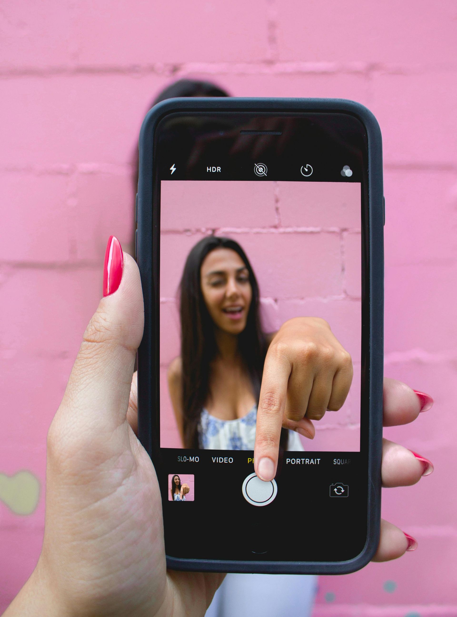 A woman is taking a picture of herself on her cell phone.