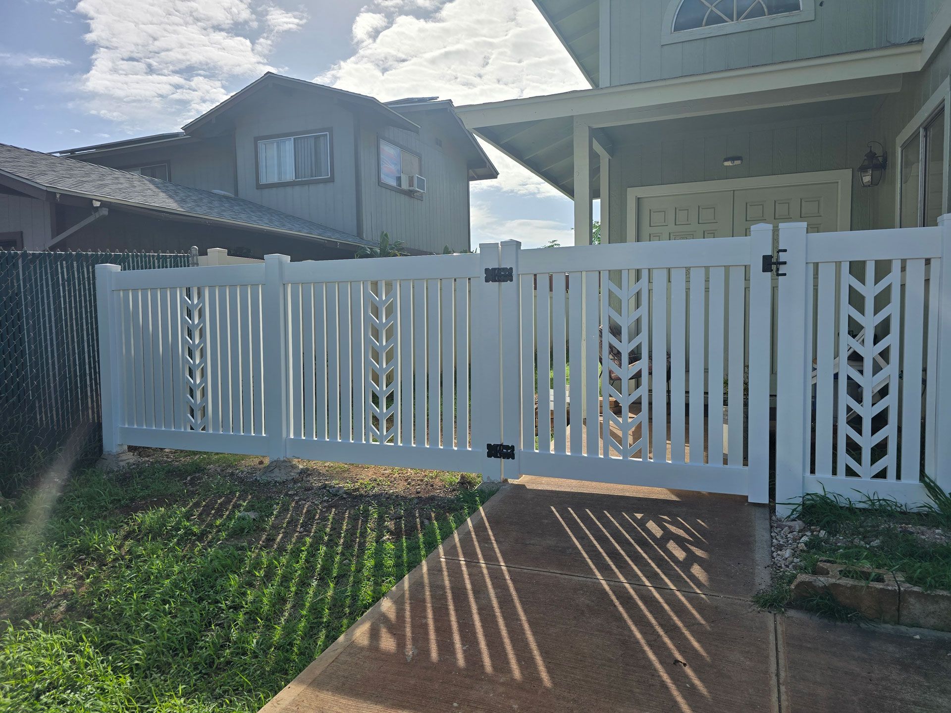 White picket fence with decorative cutouts in front of a house.