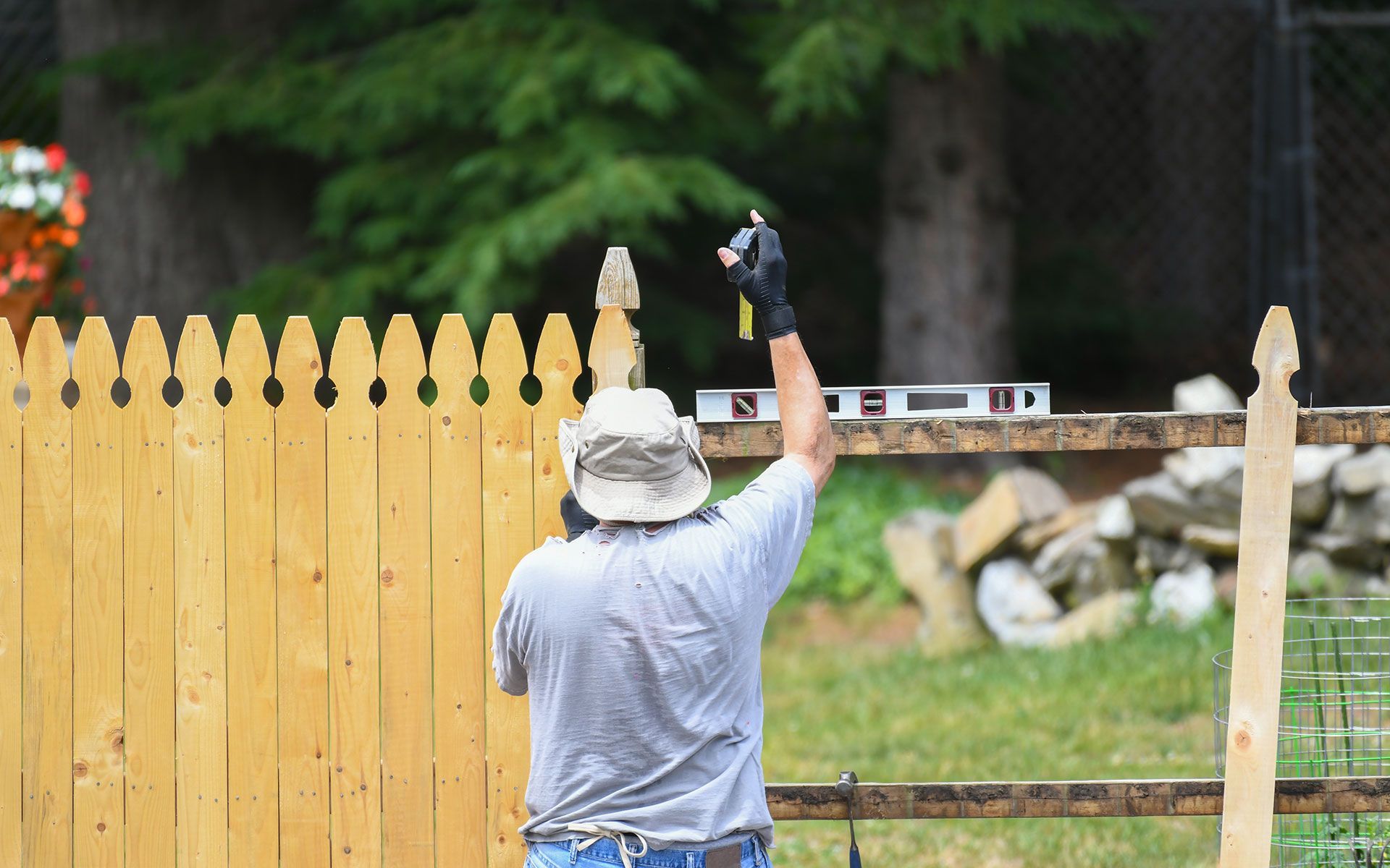 A man is measuring a wooden fence with a level.