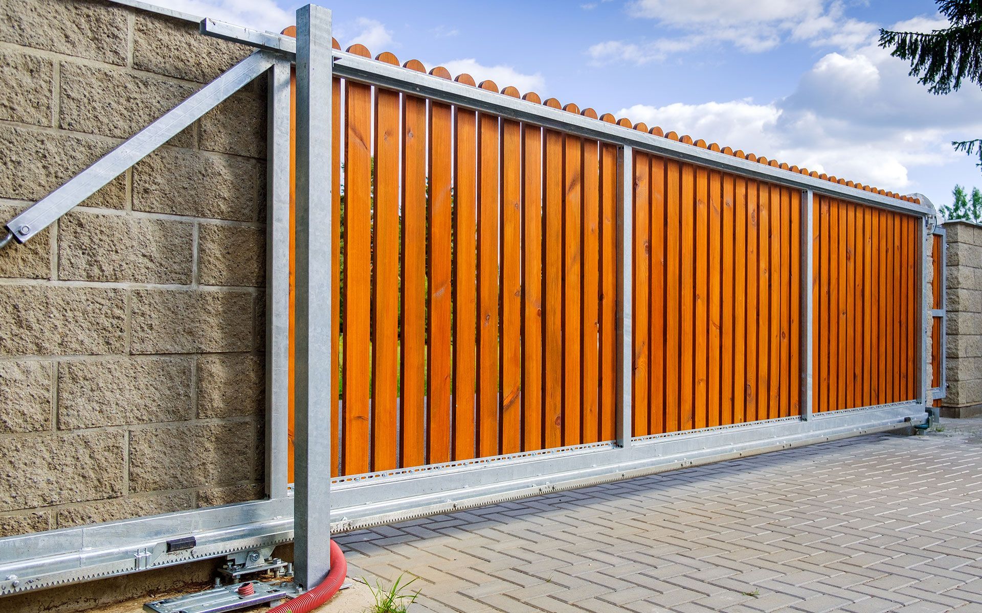A wooden sliding gate is sitting next to a brick wall.
