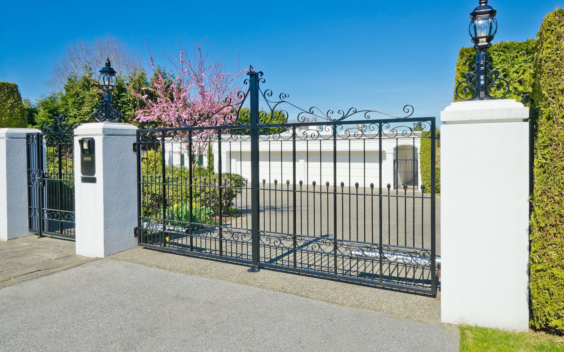 A black wrought iron gate is surrounded by white pillars