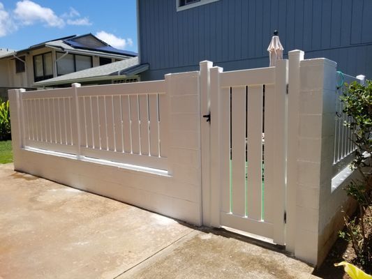 A white fence with a gate in front of a house.