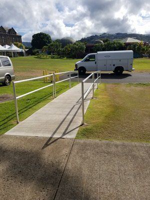 A white van is parked on the side of the road next to a ramp.