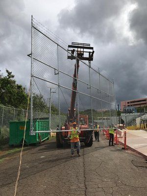 A group of construction workers are working on a chain link fence.