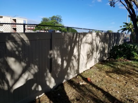A fence with a chain link fence and shadows of trees on it.