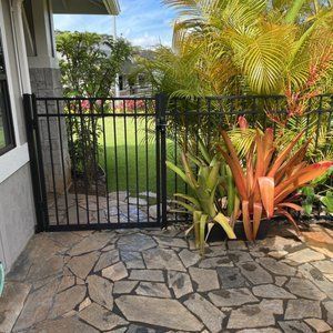 A black gate is sitting on a stone patio next to a house.