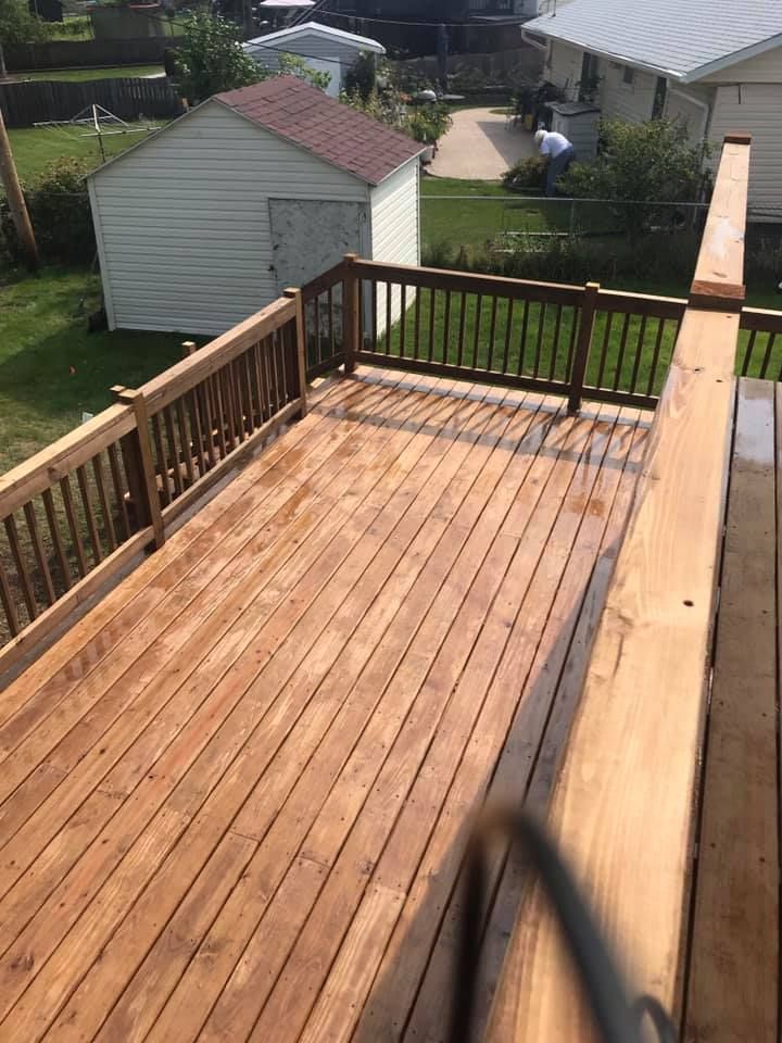 A wooden deck with a railing and a shed in the background.