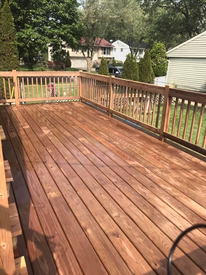 A wooden deck with a railing and a house in the background.