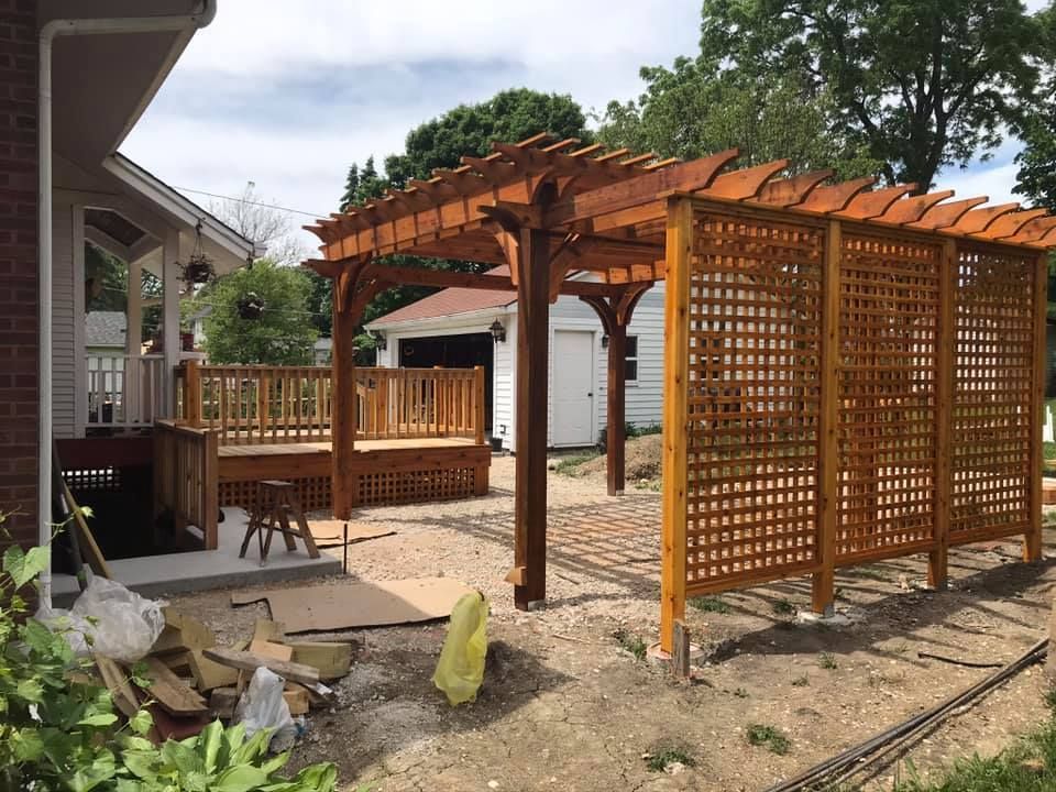 A wooden pergola is being built in the backyard of a house.