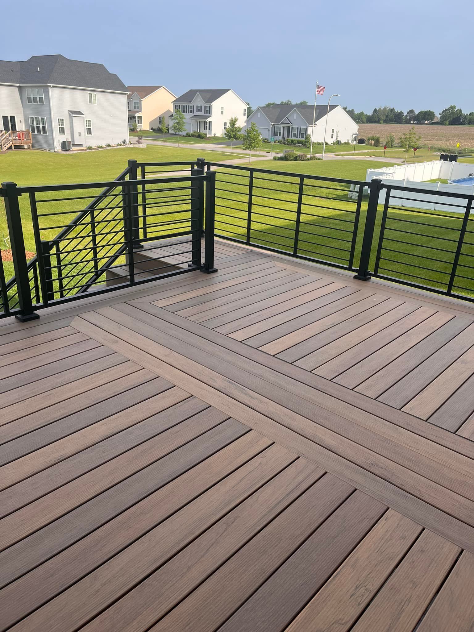 A wooden deck with a metal railing and stairs