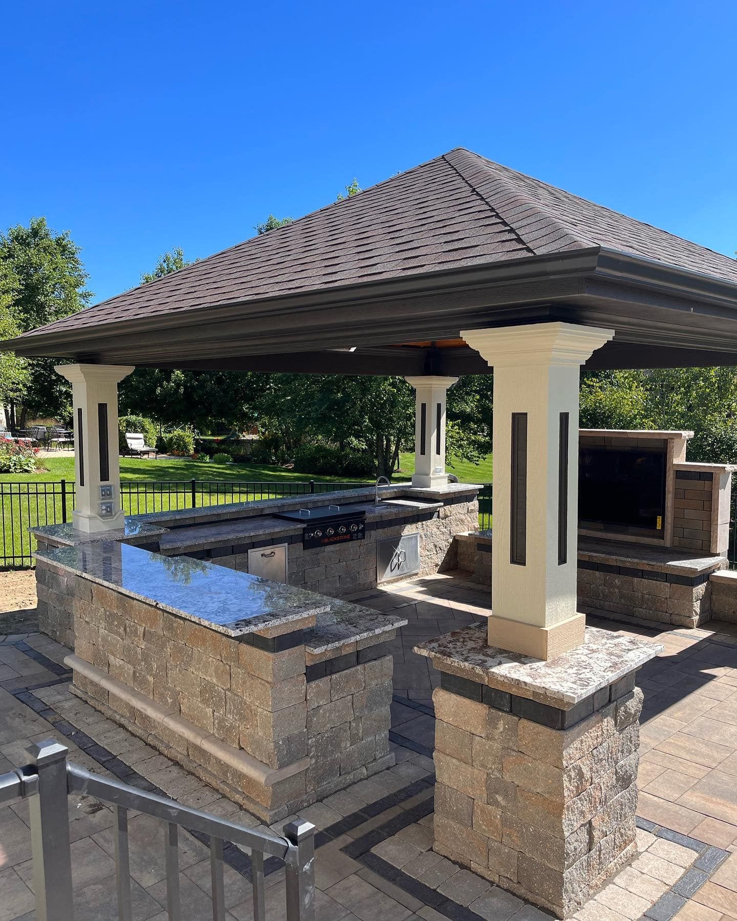 A gazebo with a grill and a fireplace underneath it