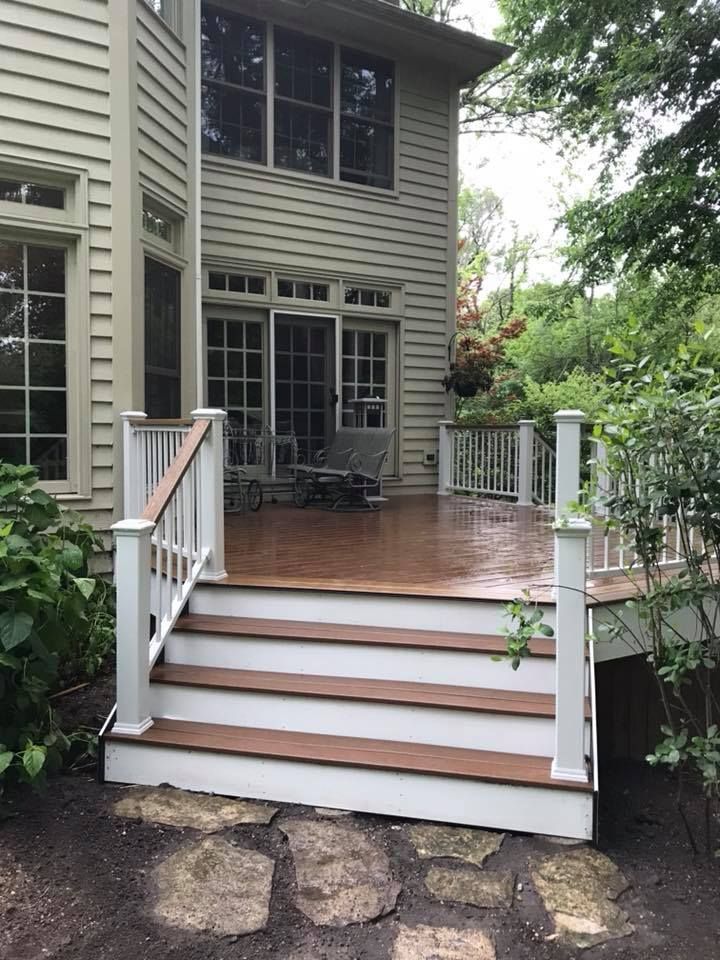 A deck with stairs leading up to it is in front of a house.