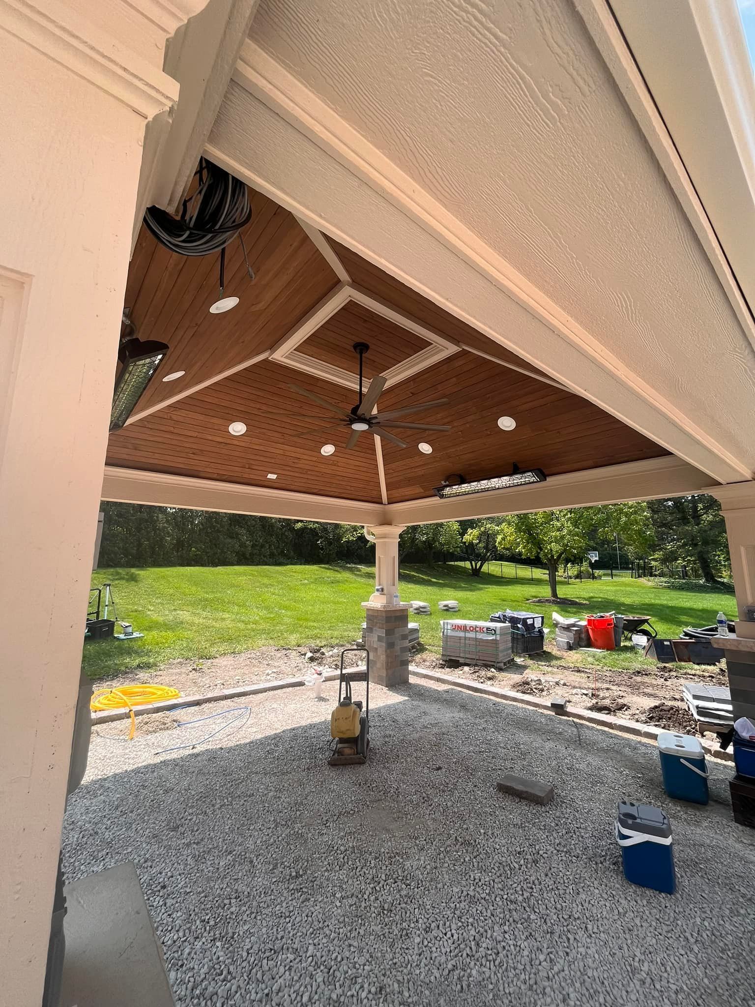 A patio with a ceiling fan and a cooler underneath it.