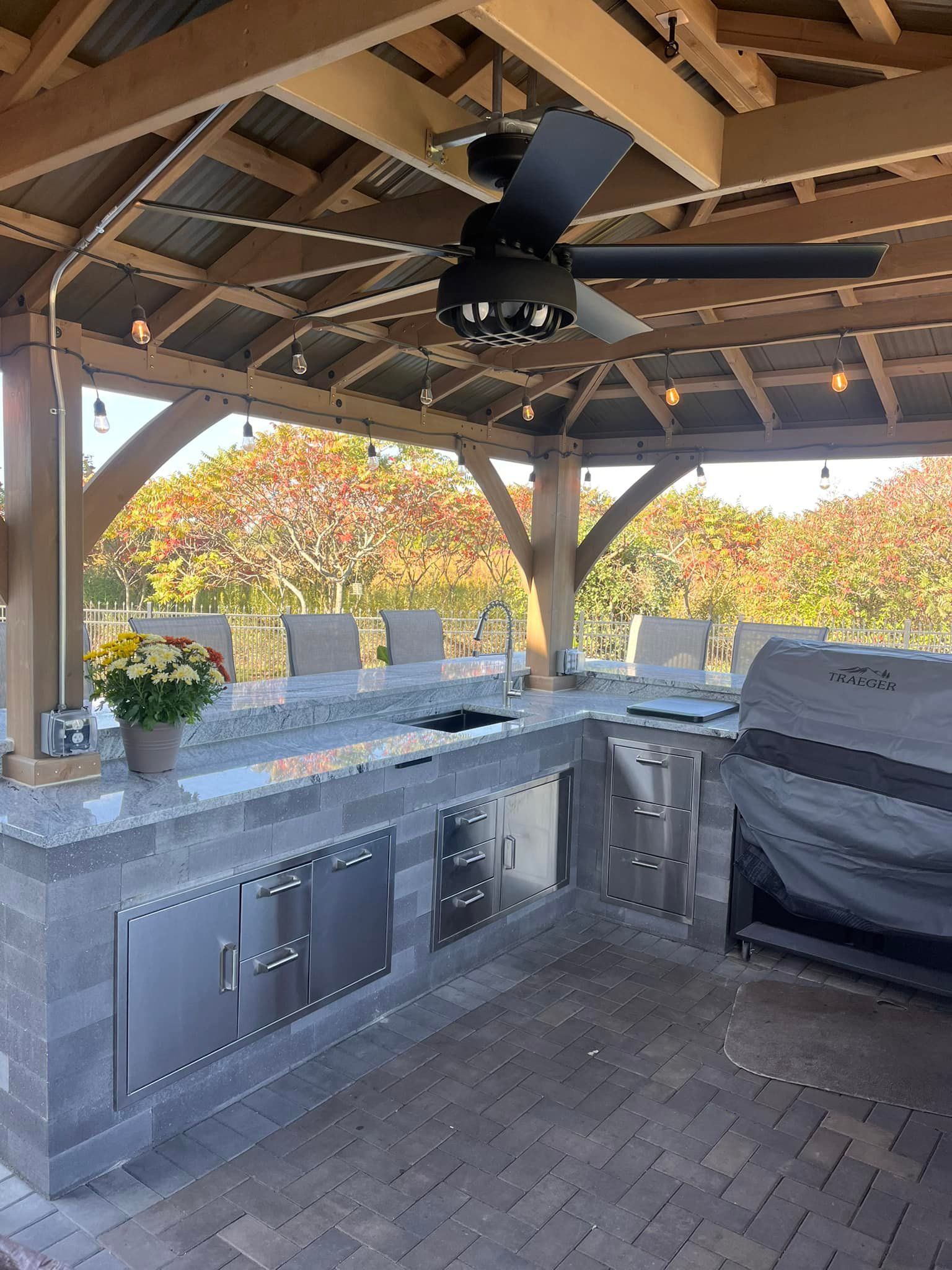 A large outdoor kitchen with a ceiling fan and a grill.