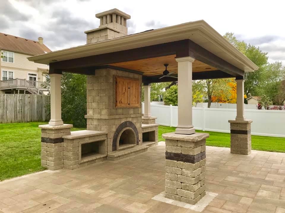 A patio with a gazebo and a fireplace in the backyard.