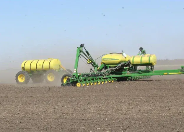 A tractor is spraying a field of plants with a sprayer.