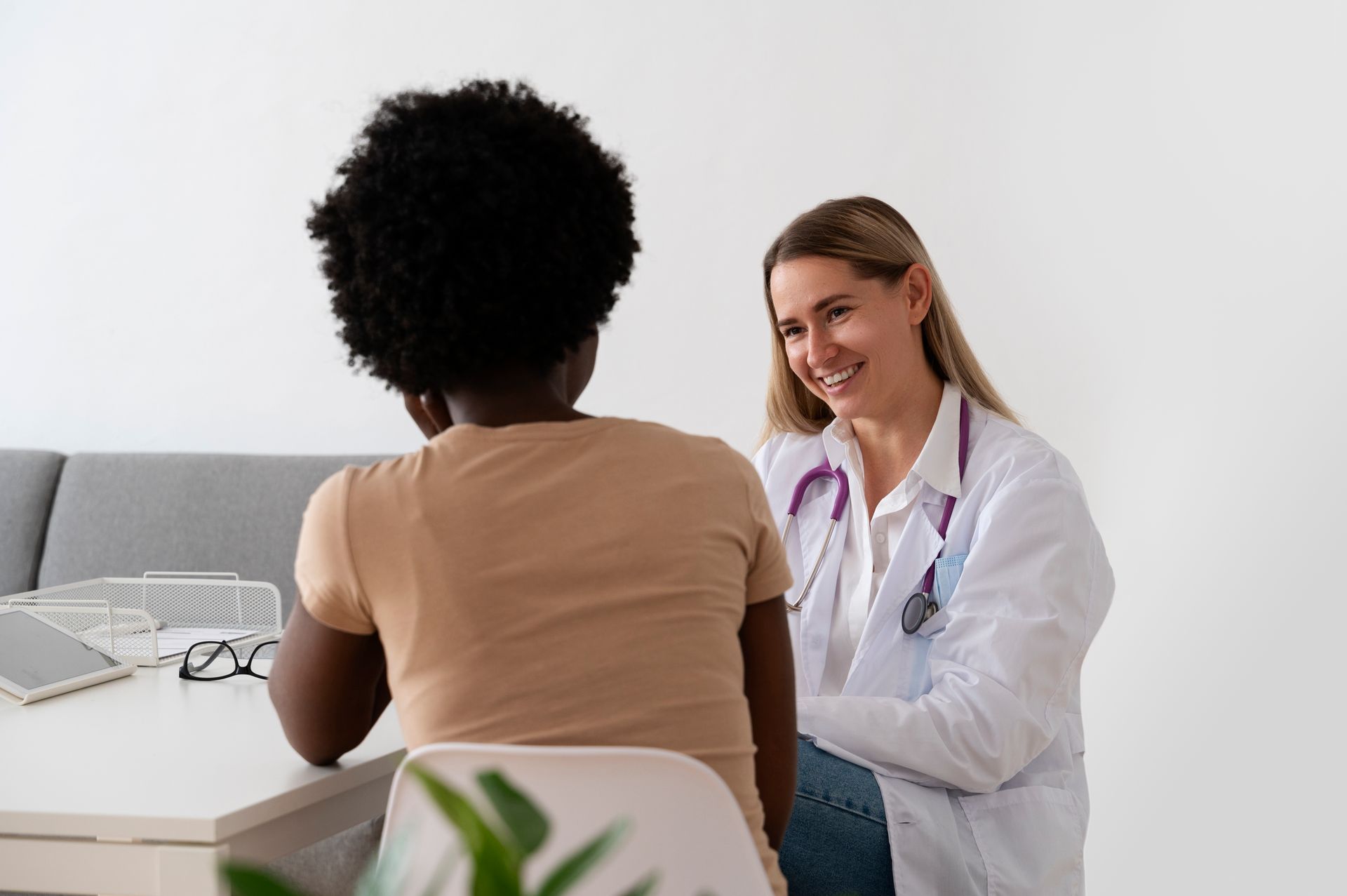 Doctor smiling at a patient while sitting at a desk in a medical office.