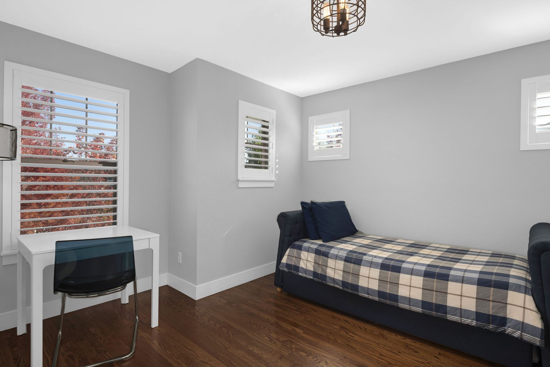 A yellow house with a green door is surrounded by trees and leaves.