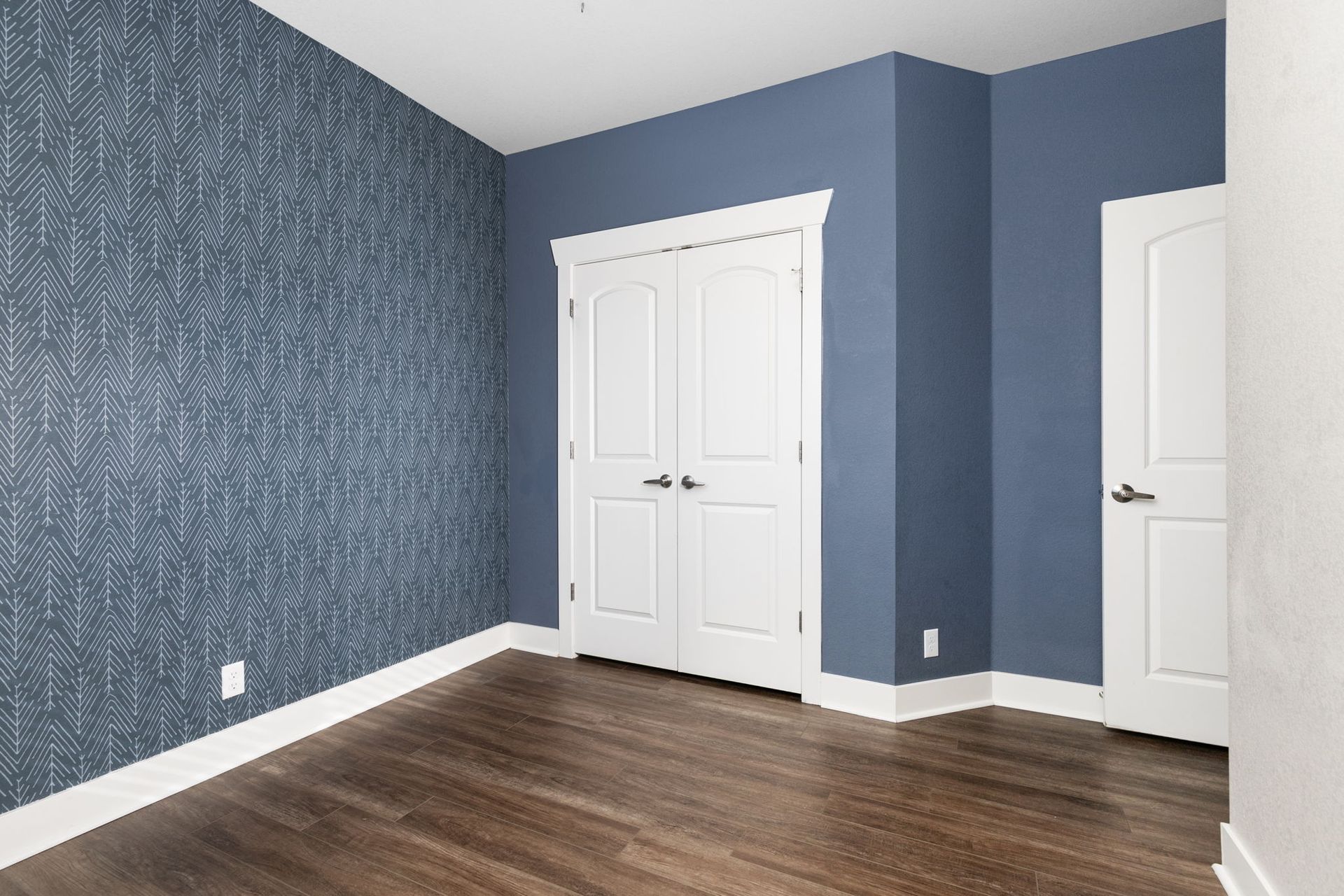 An empty basement with hardwood floors and a blue wall.