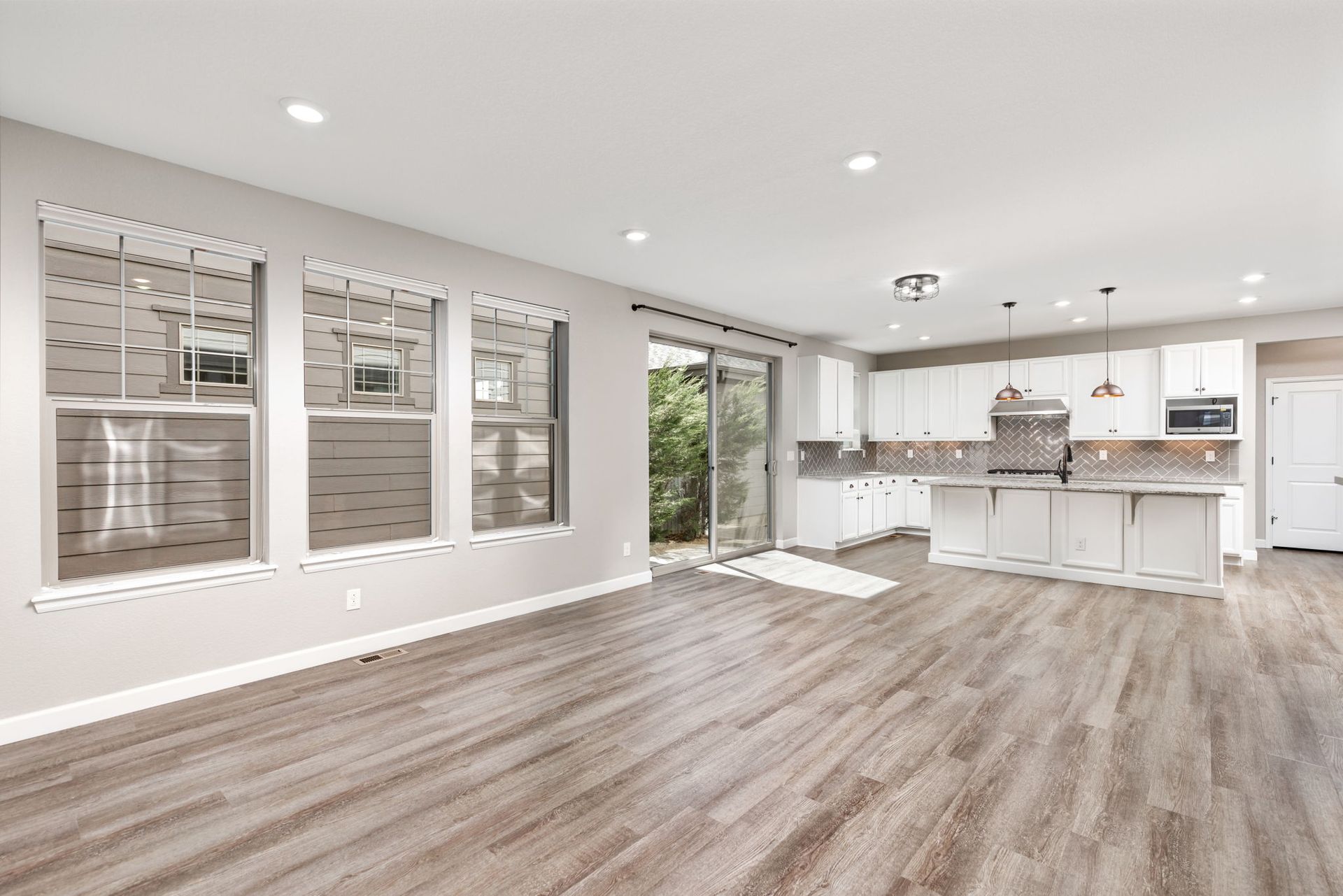 A kitchen with white cabinets , granite counter tops , stainless steel appliances and a large island.
