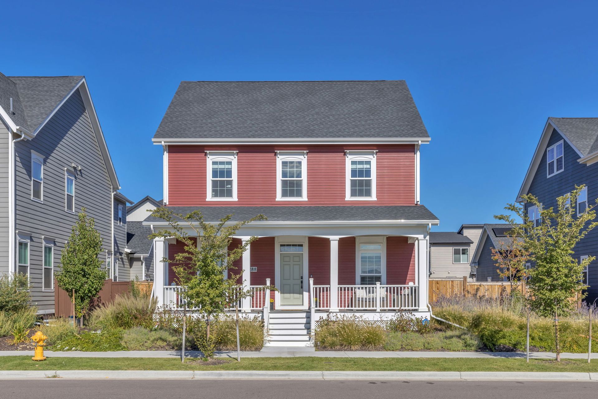 A red house with a porch and a fire hydrant in front of it