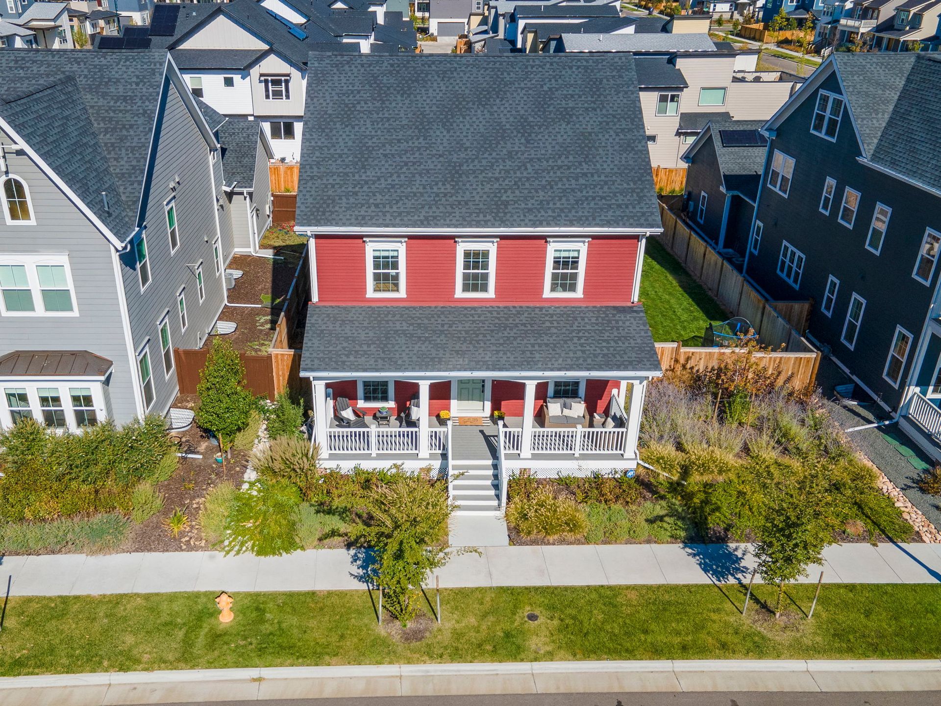 An aerial view of a red house with a porch in a residential area.