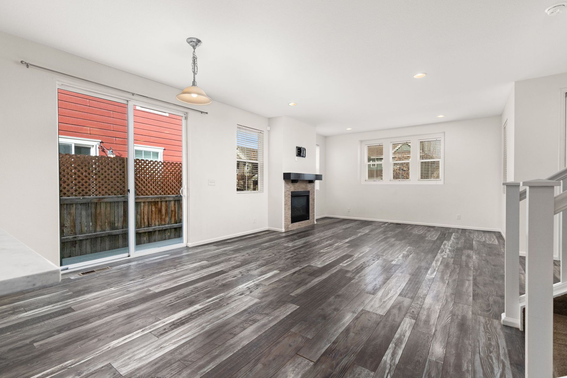 An empty living room with a carpeted floor and two windows.
