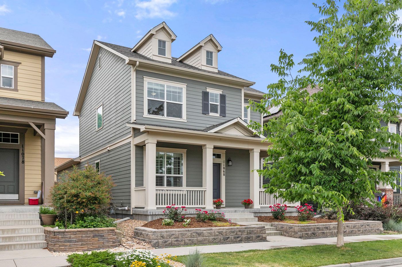 A large gray house with a porch and a lot of windows