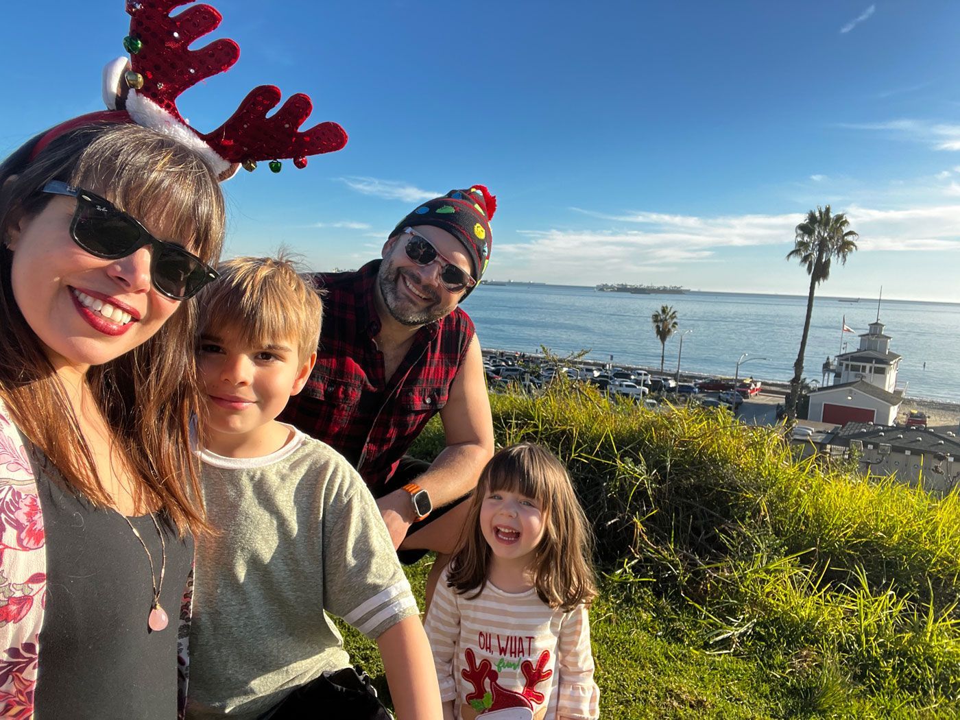 A family is posing for a picture with a lighthouse in the background.