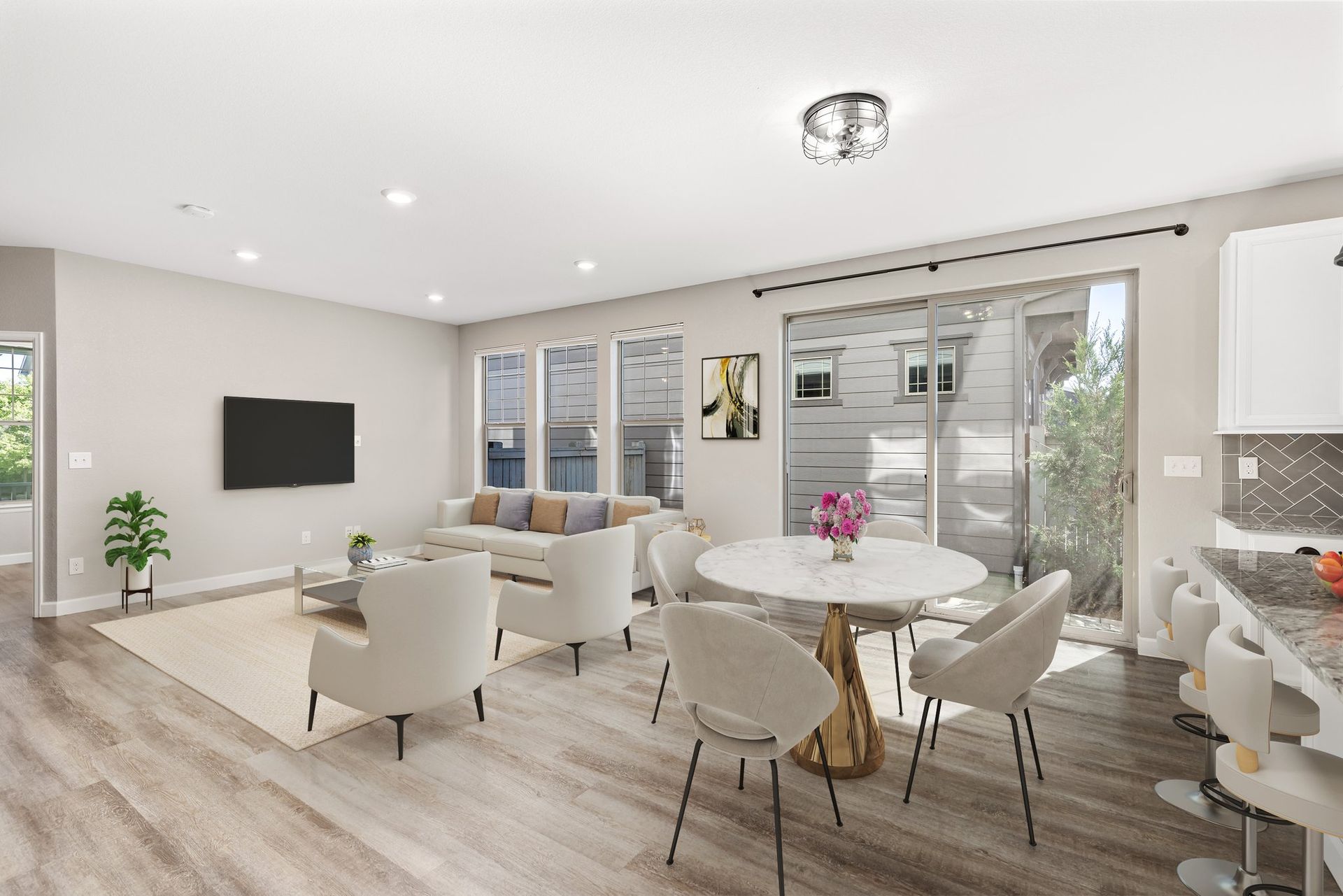 An empty living room with hardwood floors and a kitchen in the background.