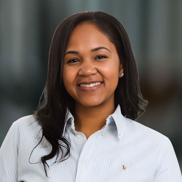 Smiling woman with light brown hair wearing a white sweater, against a blurred background.