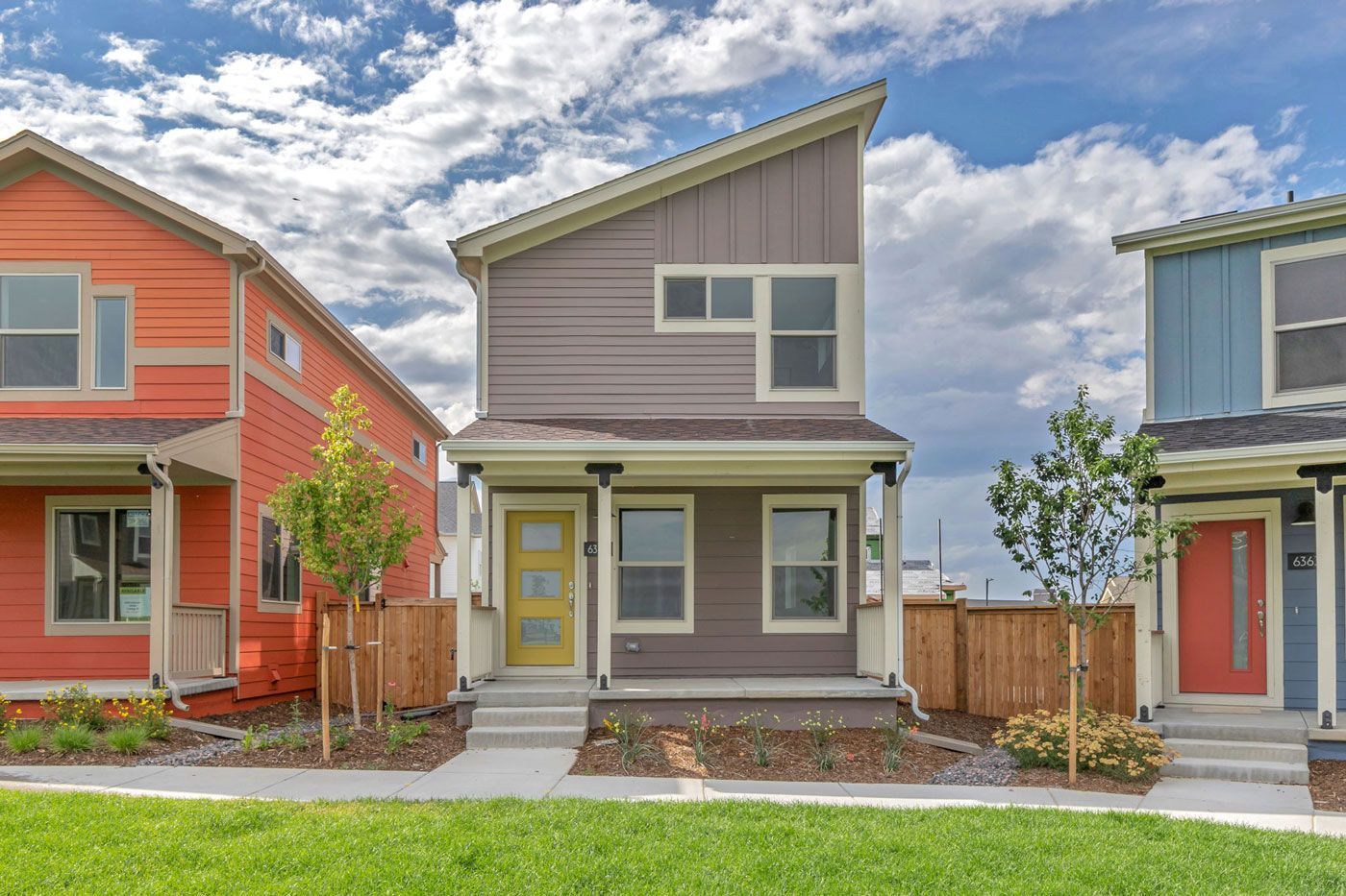 Three houses are lined up next to each other on a lush green lawn.