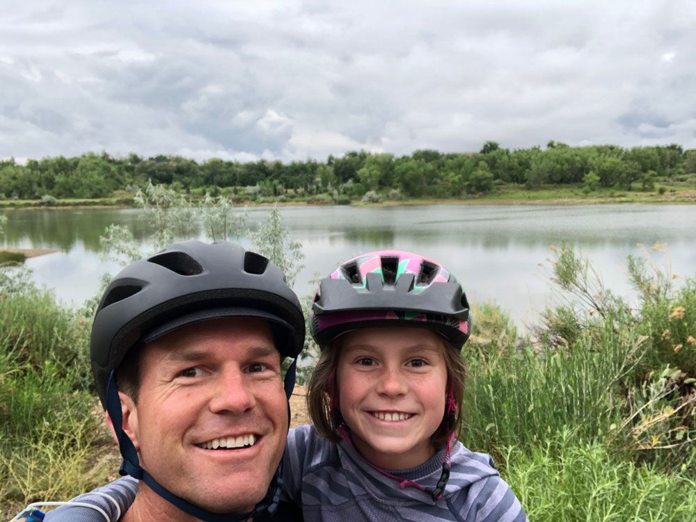 A man and a little girl wearing helmets are posing for a picture.