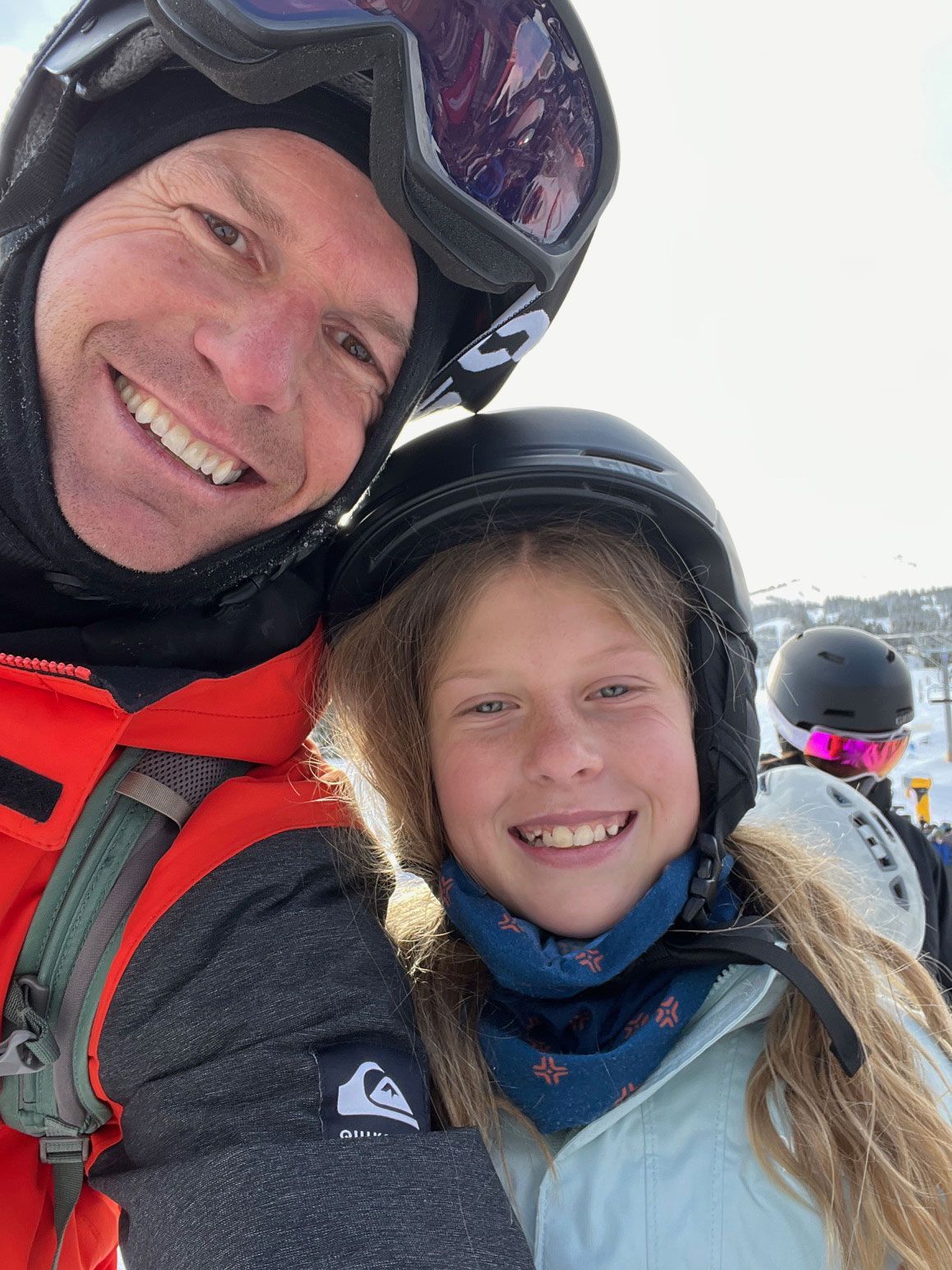 A man and a girl are posing for a picture while wearing helmets and goggles.