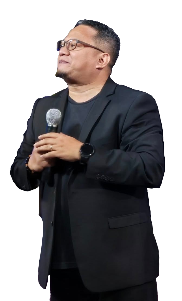 A man in a suit and glasses is standing in front of a microphone.