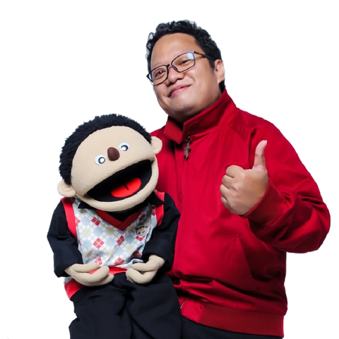 A man in a red jacket is holding a puppet and giving a thumbs up