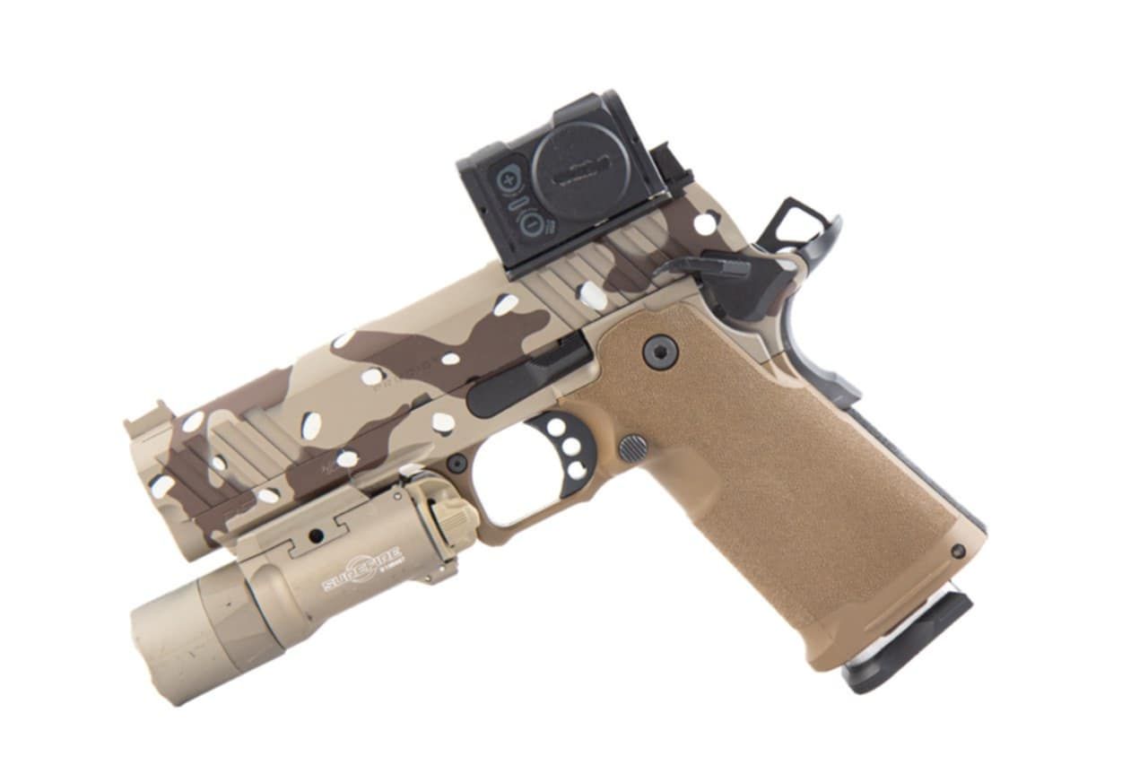 Tan and camo handgun with attached flashlight and red dot sight, isolated on white.